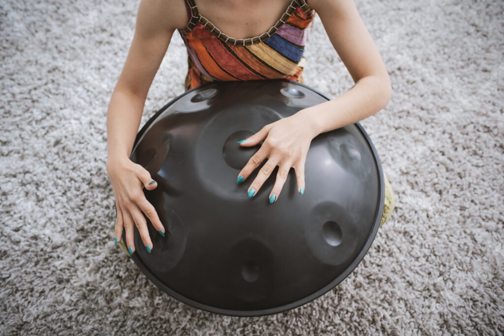 Woman playing a hang drum at home